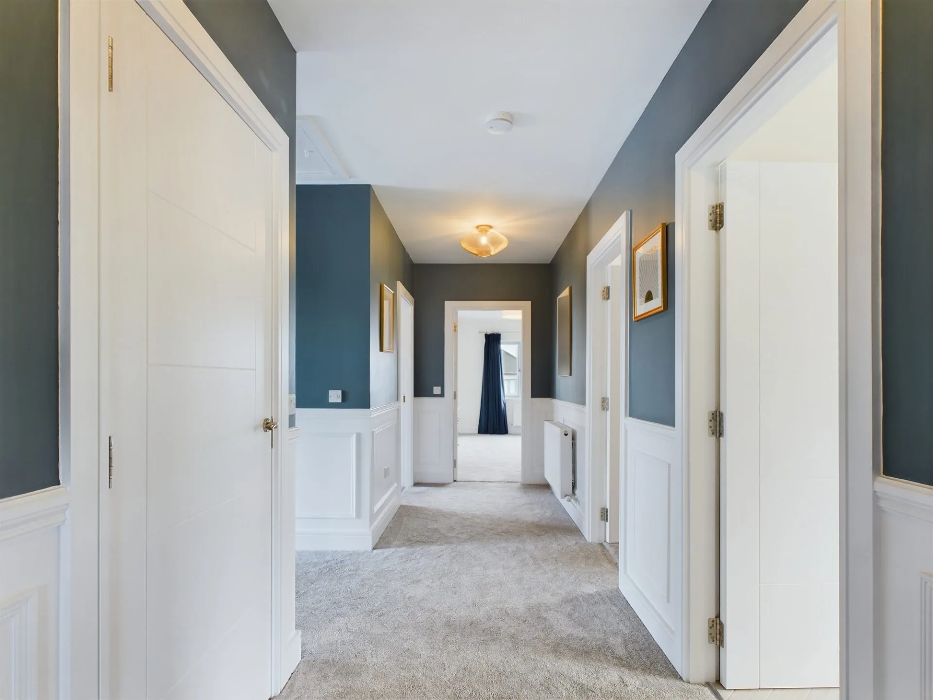 A bright hallway in a spacious large house with bright lighting and white doors