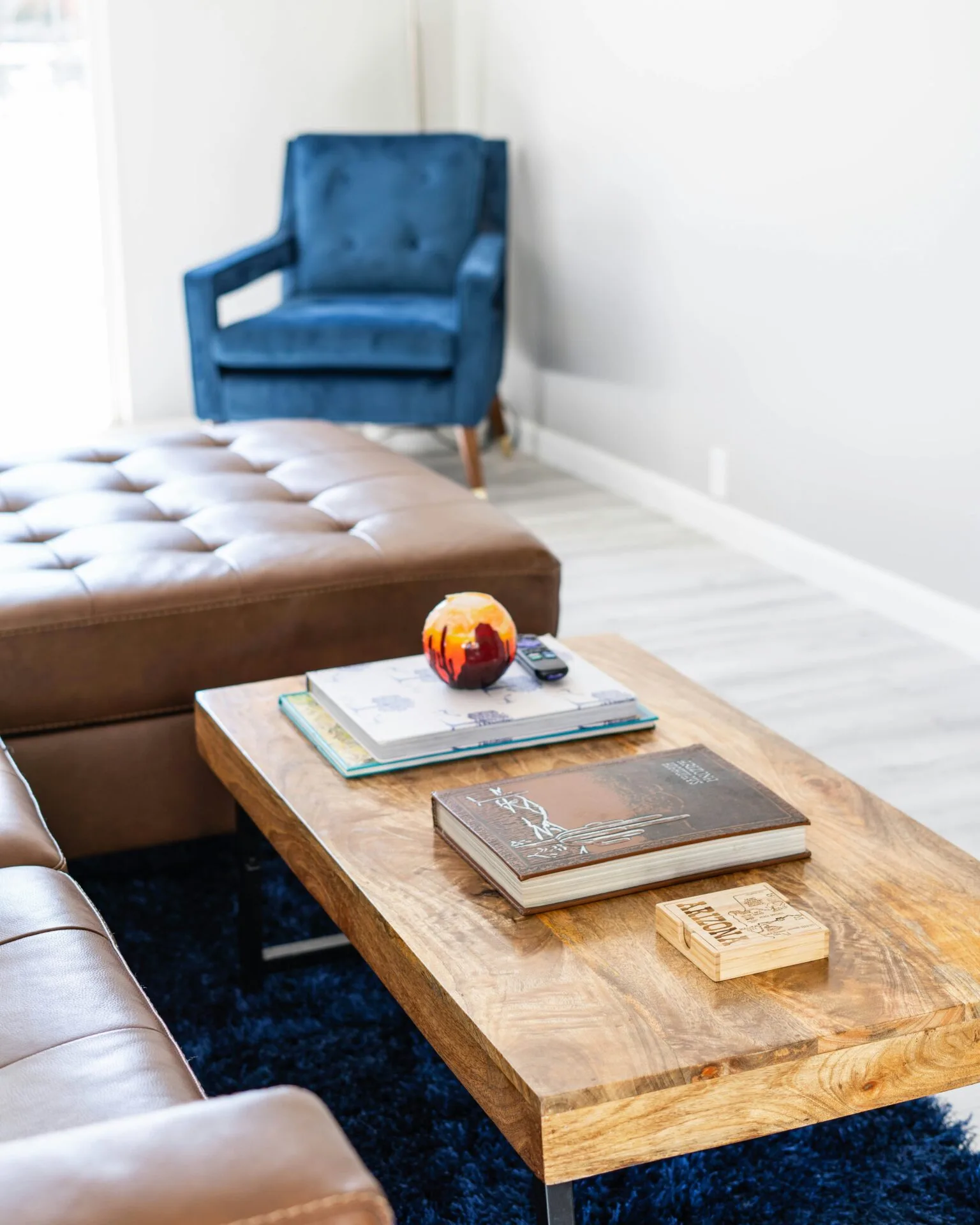 A living room with coffee table, books and a blue chair